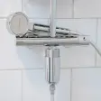 Håndbruser i krom på en termostatarmatur med et cylinderformet filterhus i blank krom monteret under armaturet